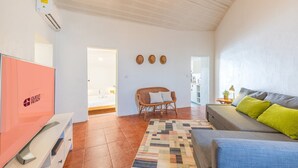 Une pièce comprenant un lit, une chaise en osier, un canapé, un tapis à motifs et un coin cuisine.