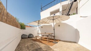 Une terrasse avec une table et des chaises, un grand parasol et deux fauteuils en forme de sac.