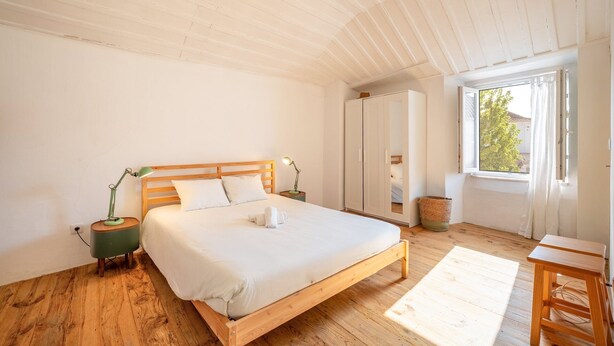 Une chambre à coucher avec un lit en bois, des lampes de chevet, une fenêtre donnant sur un beau paysage et une petite table.