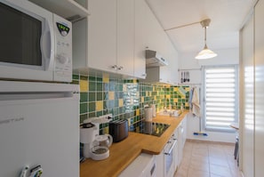 A kitchen with white cabinets, a microwave, a coffee maker, and a toaster.