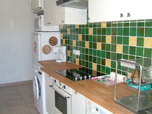 A kitchen with a washing machine, microwave, and a tiled backsplash.