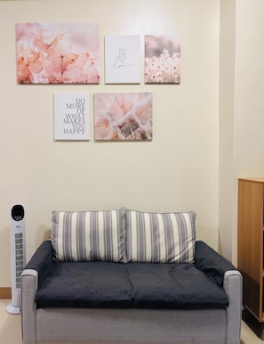 A living room with a sofa, a wall-mounted heater, and four framed motivational quotes.