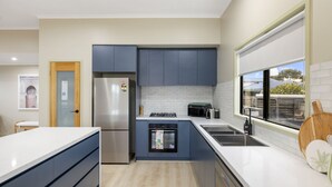 Una cocina moderna con armarios grises, un refrigerador de acero inoxidable, un horno empotrado y una ventana con vistas al exterior.