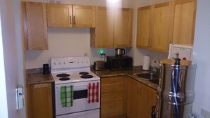 Una pequeña cocina con armarios de madera, una estufa blanca, un tostador y un lavamanos.