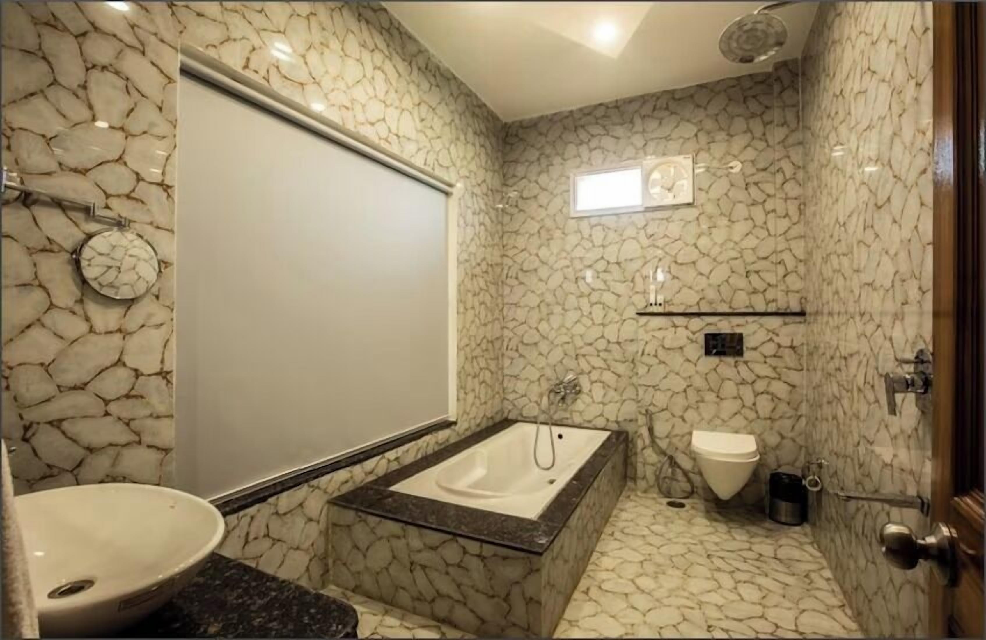 A bathroom with a stone-patterned wall, a bathtub, a toilet, and a sink.