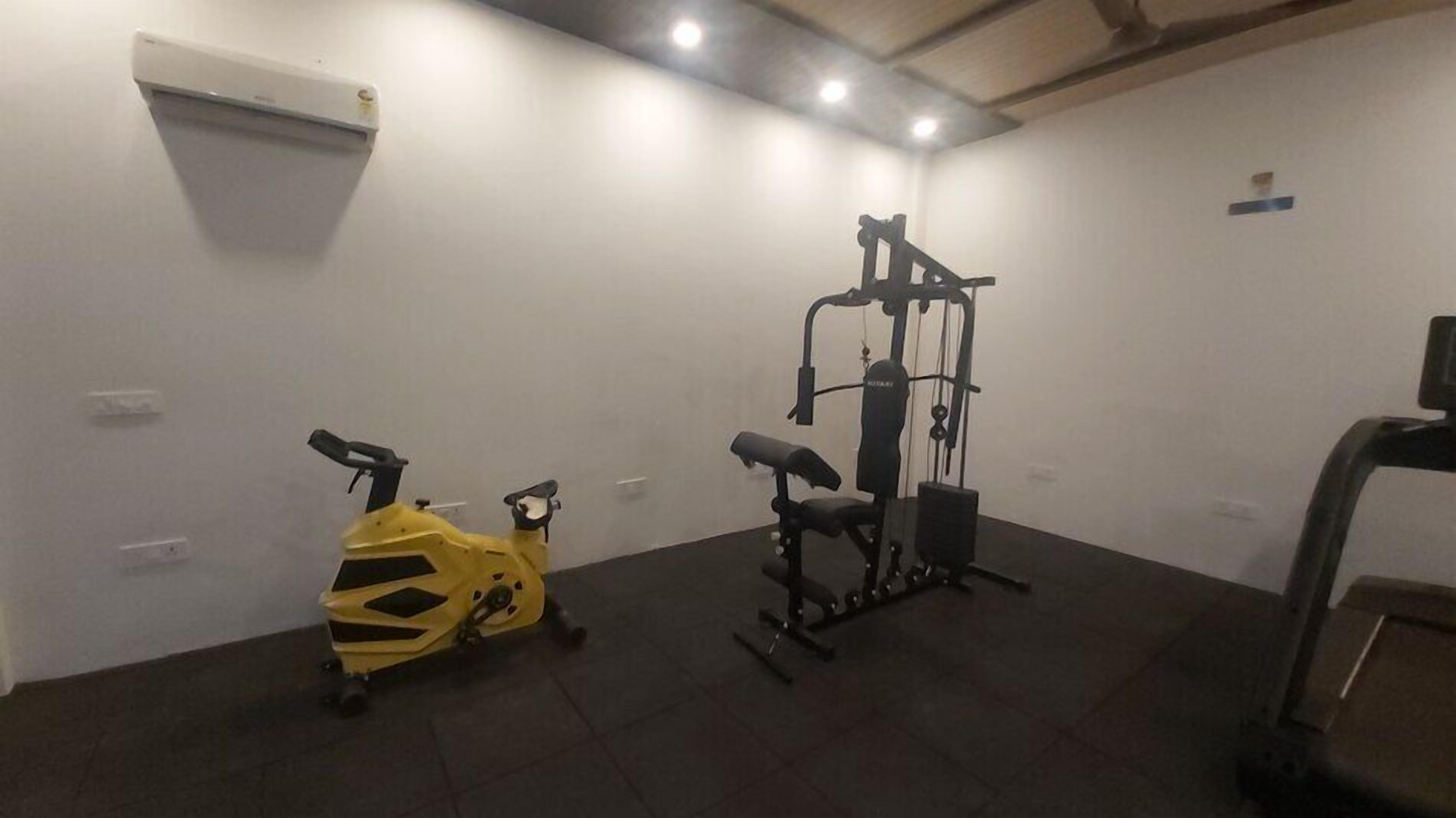 A gym with a stationary bike, a weight machine, and a treadmill.