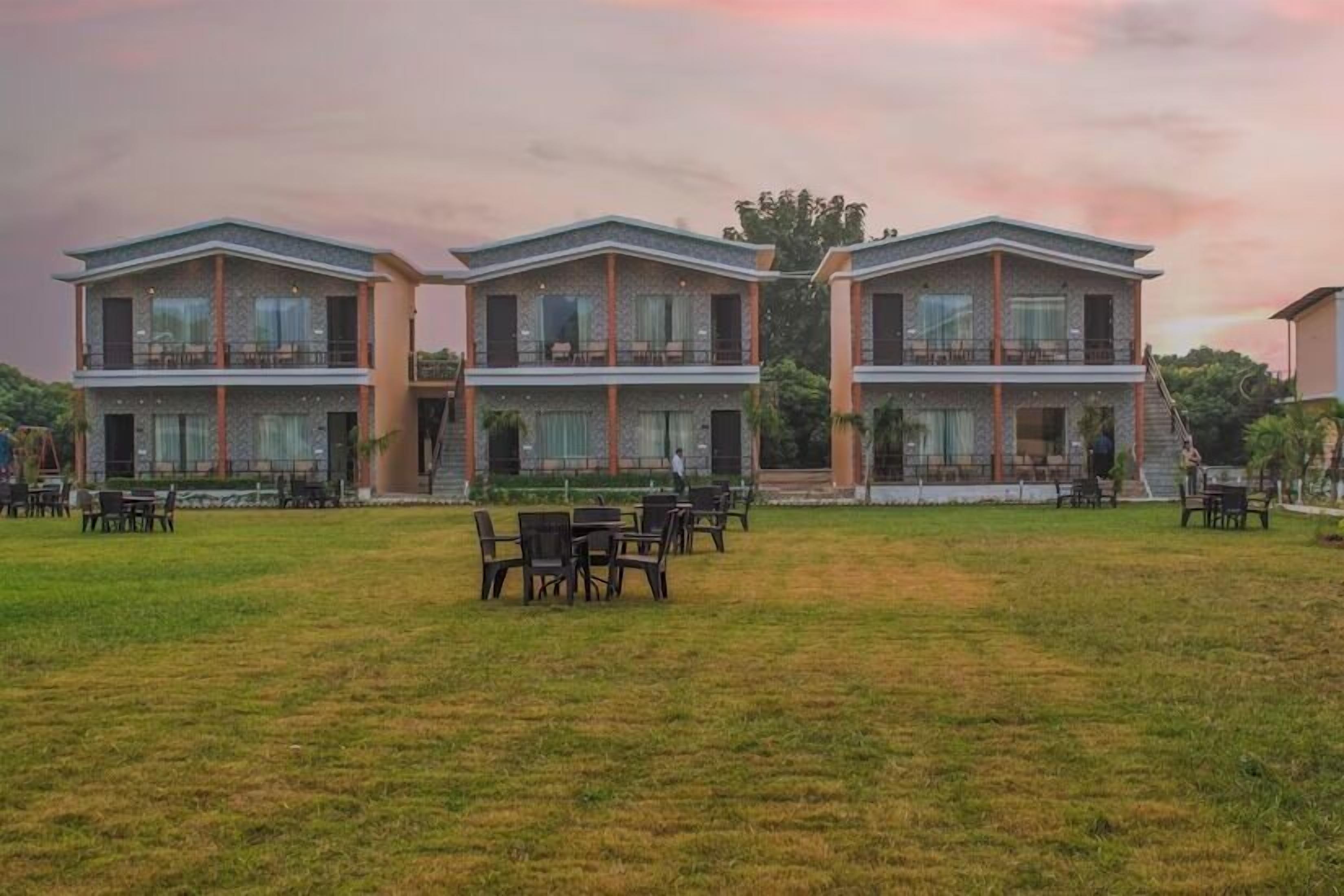 Un hotel con edificios de tres pisos, asientos al aire libre y un patio cubierto de césped.
