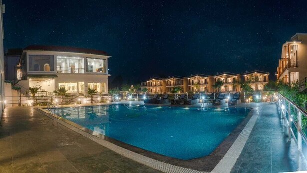 Ein Hotel bei Nacht mit Schwimmbad, mehreren Gästezimmern und einem gut beleuchteten Außenbereich.