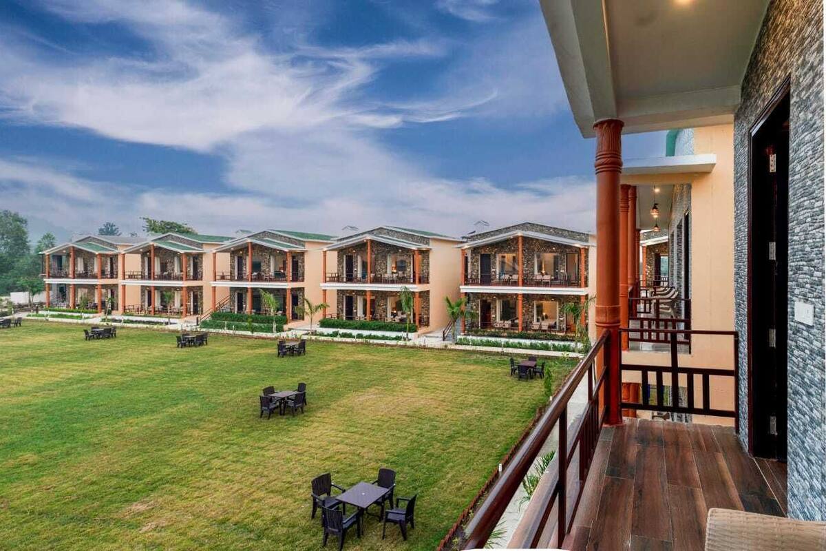 Ein Hotel mit mehreren Gästezimmern, einer großen Grünfläche und Sitzgelegenheiten im Freien.