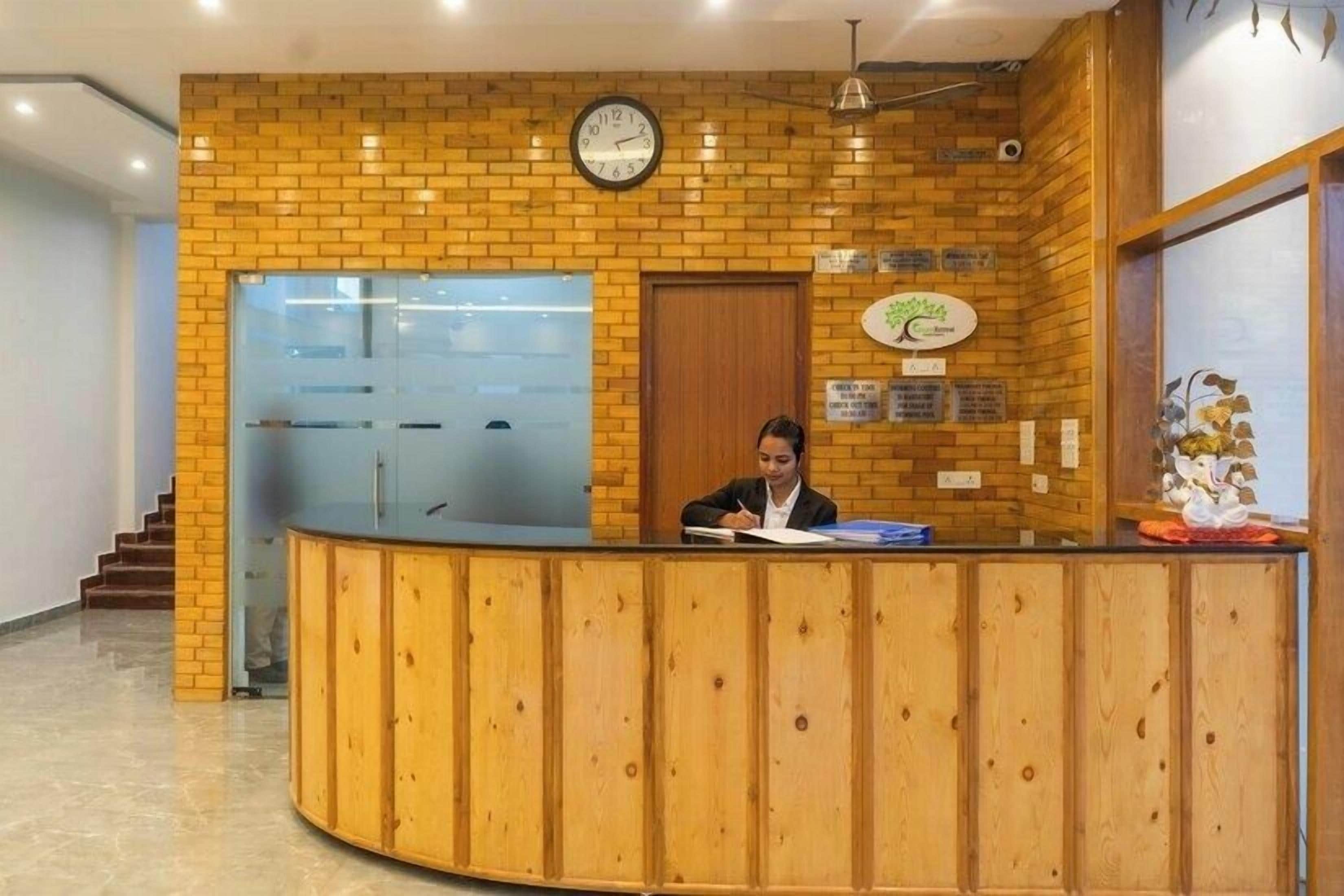 A reception desk with a clock, wooden paneling, and a glass door.