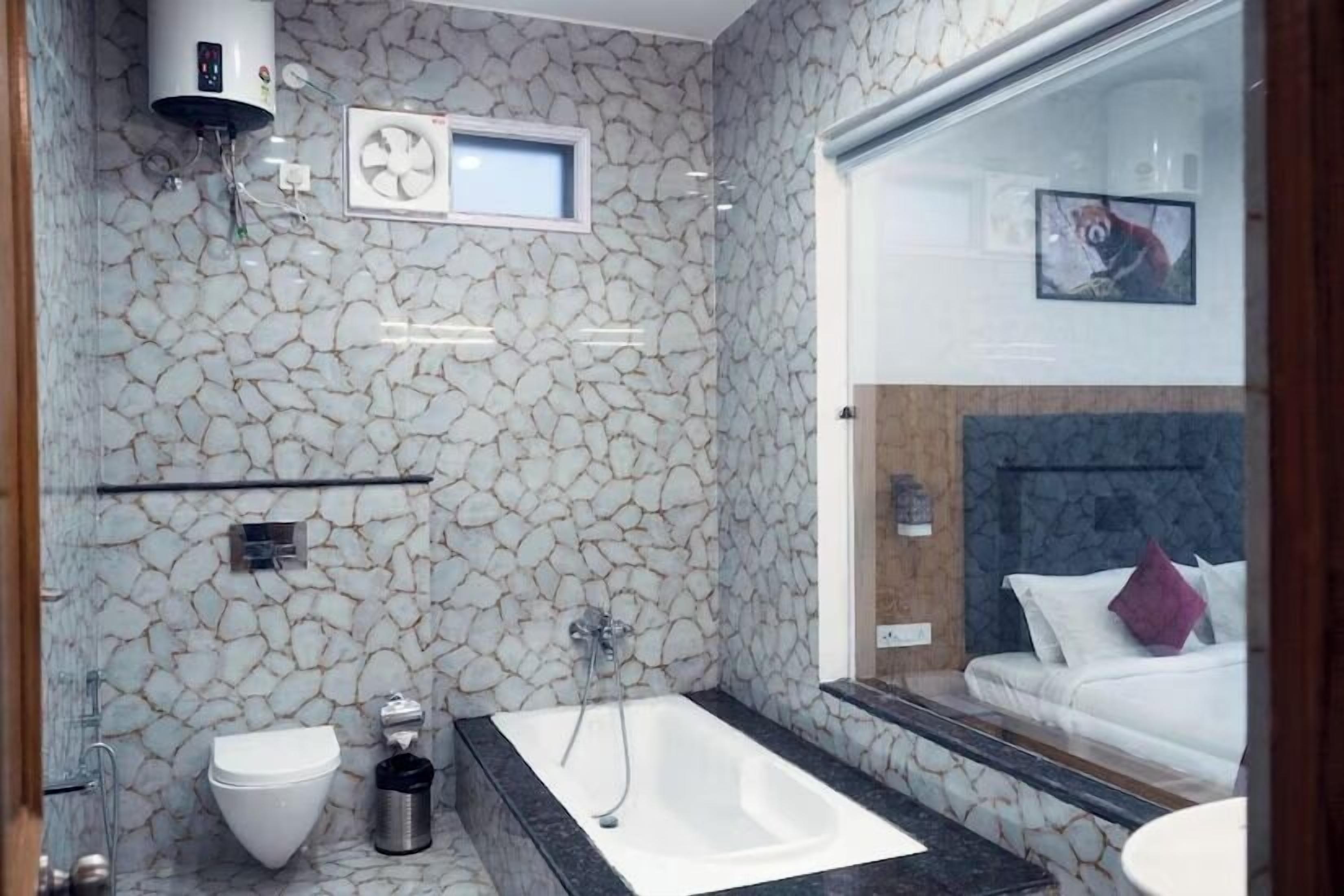 A modern bathroom with a stone-patterned wall, a white bathtub, a toilet, and a sink.