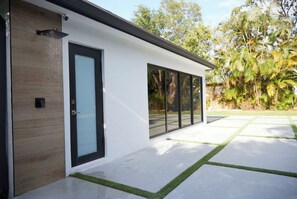Una casa moderna con un amplio ventanal, fachada de madera y césped cuidado.