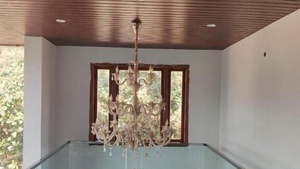 A modern interior with a wooden ceiling, a glass balcony, and a chandelier. - HOTEL GREENLAND INN HAMPI (Hospet)