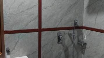 Zona de ducha con lavamanos blanco y cabezal de ducha de mano.
