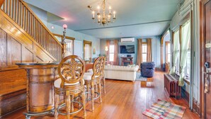 A spacious living room with a wooden staircase, a chandelier, and a fireplace. - Fire Pits, Views & Yard: Luxe Mt Horeb Getaway! (Mt Horeb)