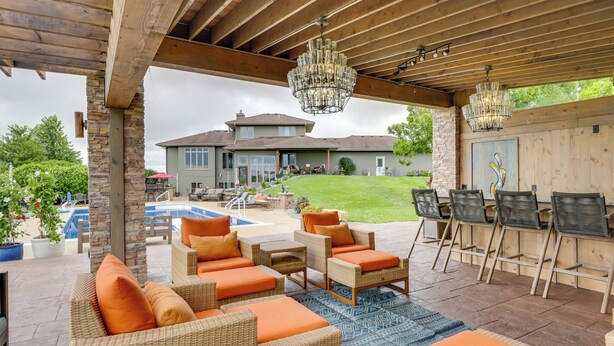 A covered outdoor patio with wicker furniture, a pool, and a bar area. - Outdoor Oasis: Luxe Flat in Mt Horeb! (Mt Horeb)