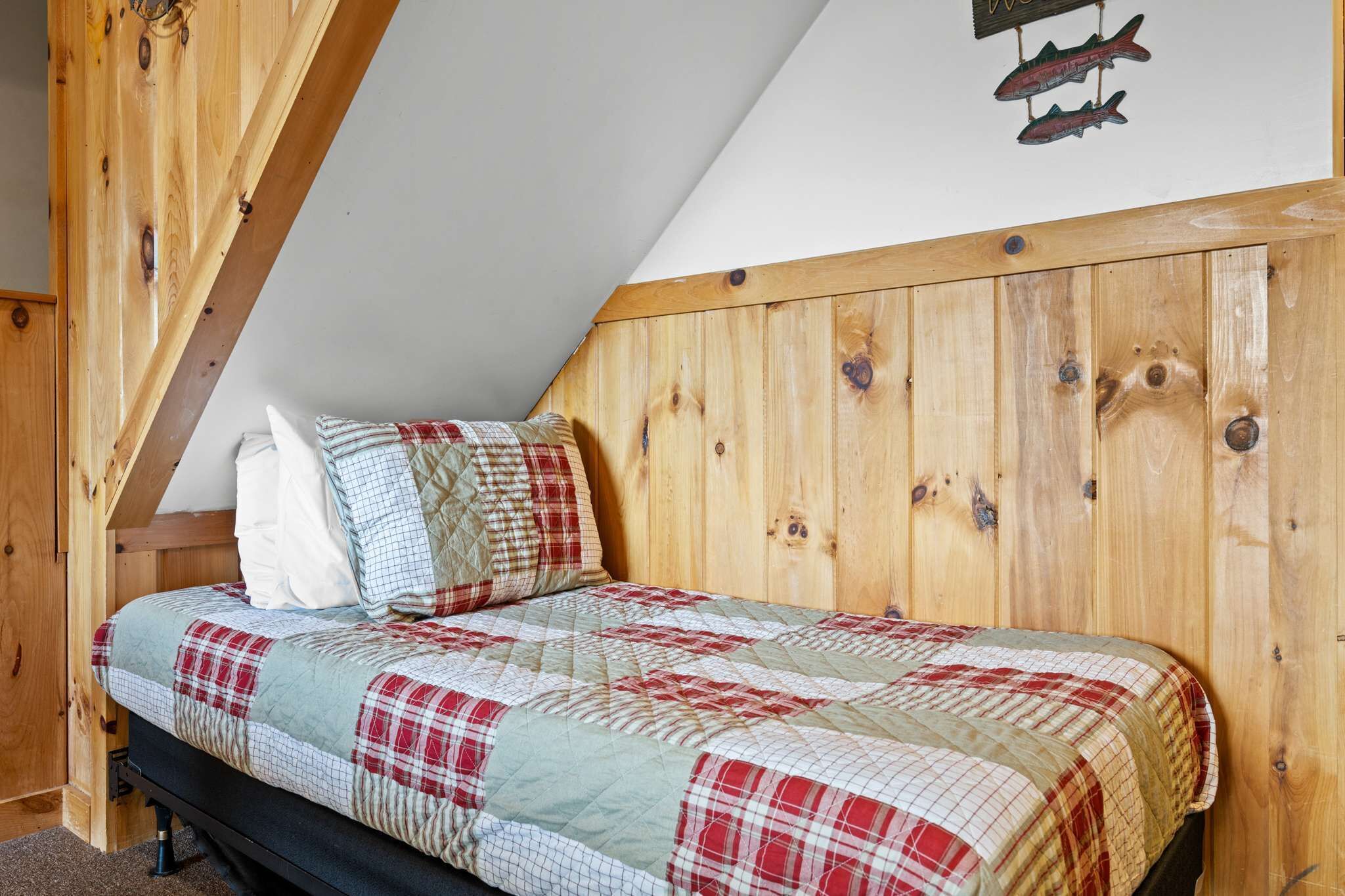 Un dormitorio con cabecera de madera, cama con colcha a cuadros y decoración de peces en la pared.