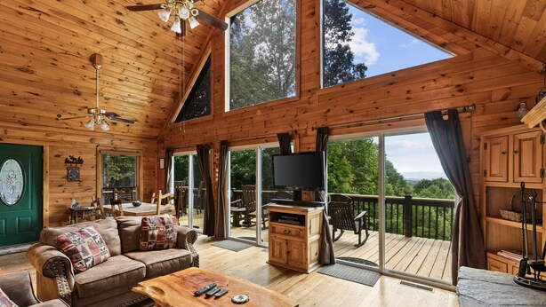 A spacious wooden cabin with a large living area, a balcony, and a television.