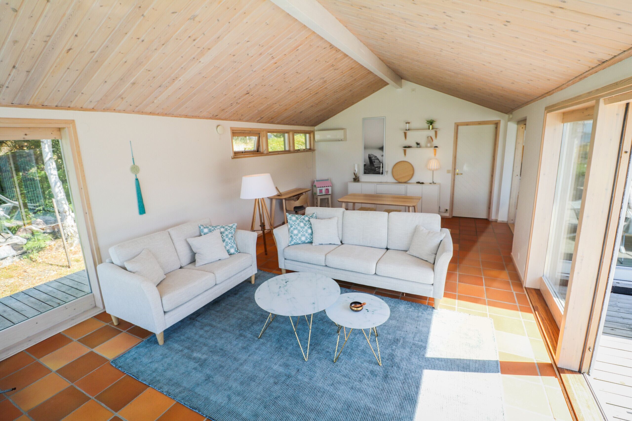 A spacious living area with a high ceiling, a white sofa set, two round coffee tables, and a blue rug.