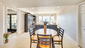 A dining area with a round table, four chairs, and a vase. There is a kitchen area with cabinets and a countertop visible in the background. - Puget Sound Views: Des Moines Apt w/ Patio (Des Moines)