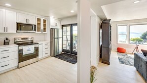 A modern kitchen with white cabinets, stainless steel appliances, and a view to the outside. - Puget Sound Views: Des Moines Apt w/ Patio (Des Moines)