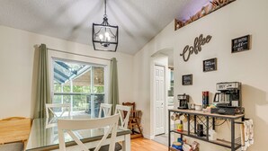 A dining area with a glass table, white chairs, and a coffee station with brewing equipment. - Private Backyard Oasis: Cocoa Family Home! (Cocoa)