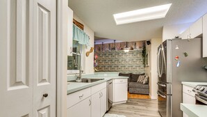A modern kitchen with white cabinetry, a stainless steel refrigerator, and a built-in oven. - Private Backyard Oasis: Cocoa Family Home! (Cocoa)