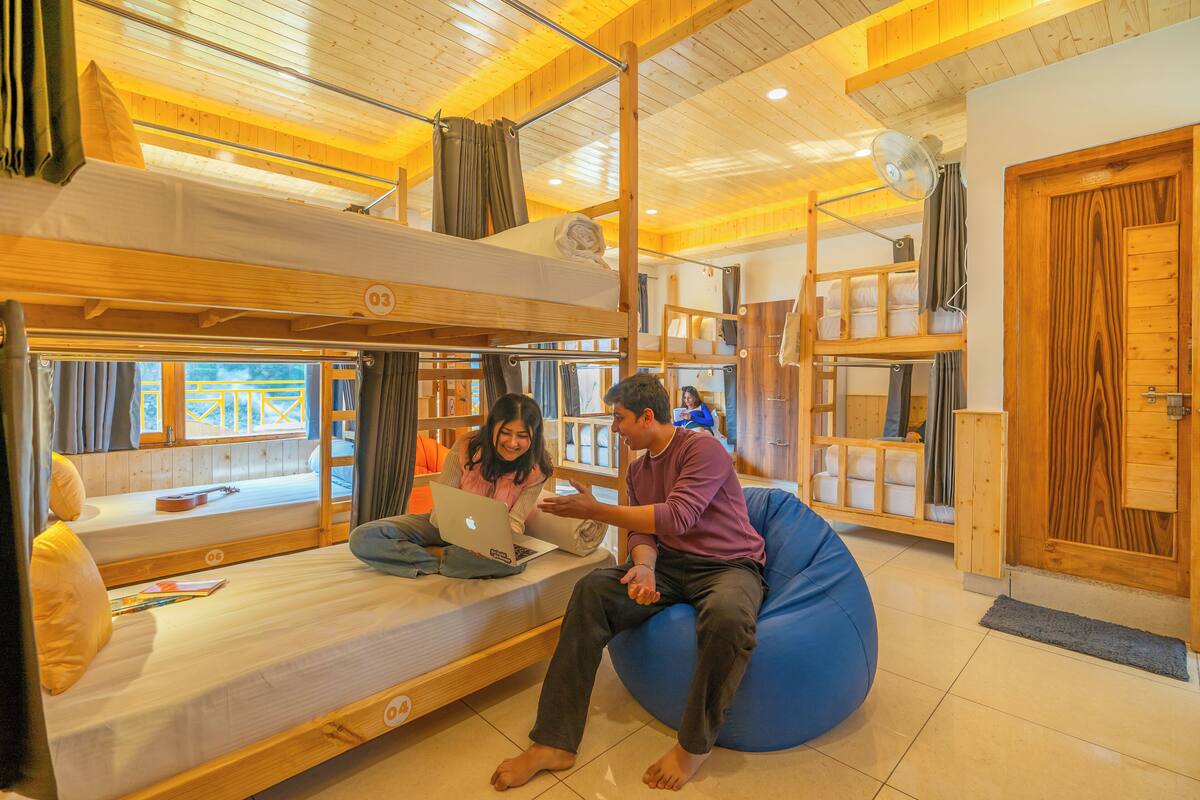 A bunk bed room with a laptop on the lower bunk, a blue bean bag chair, and wooden walls.