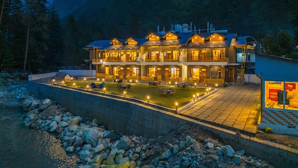 Een groot, meerlaags hotel met een goed verlicht buitengebied, omringd door bergen.