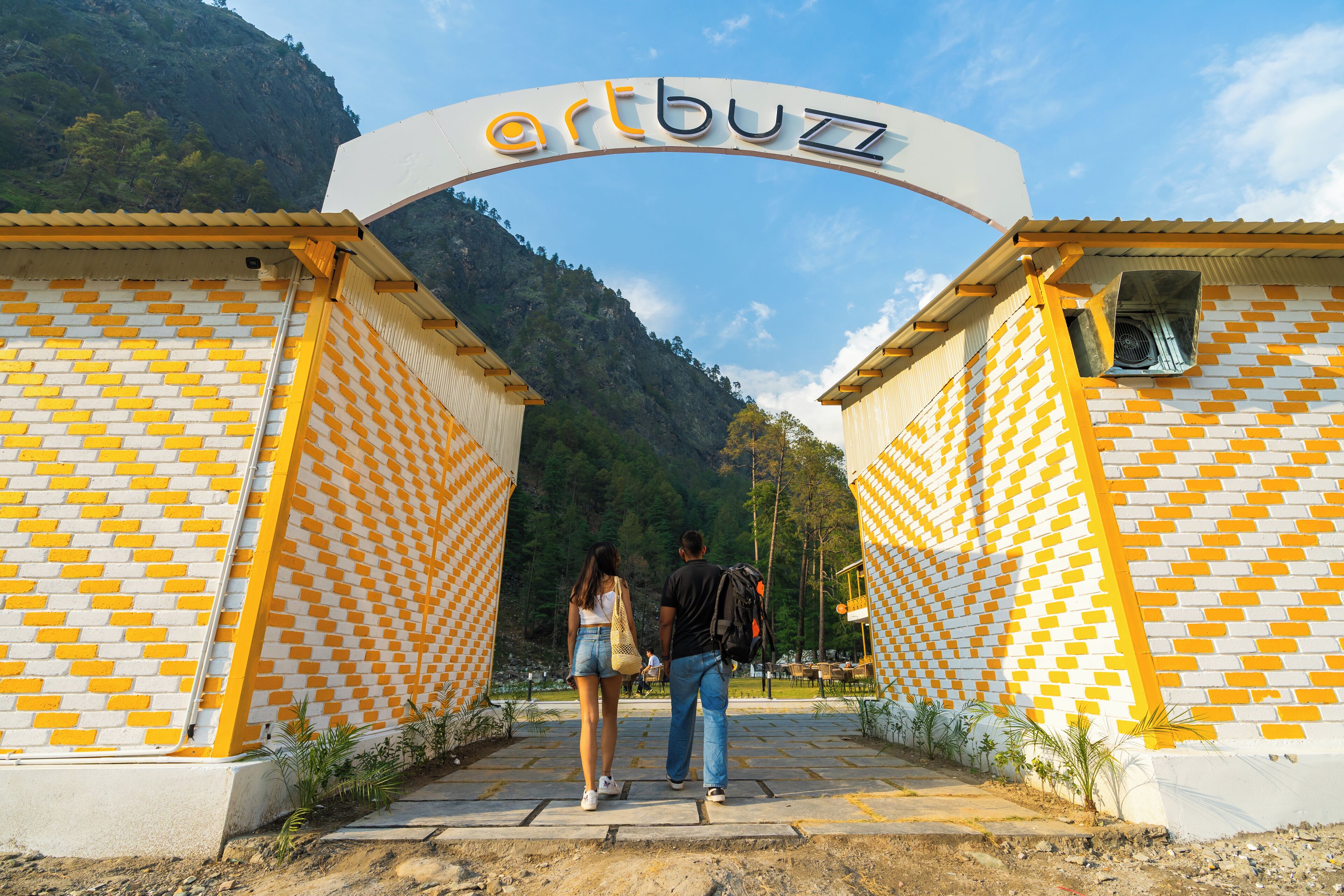 Entrada de un edificio con un letrero que dice 'artbuzz' y un patrón de pared de ladrillos.