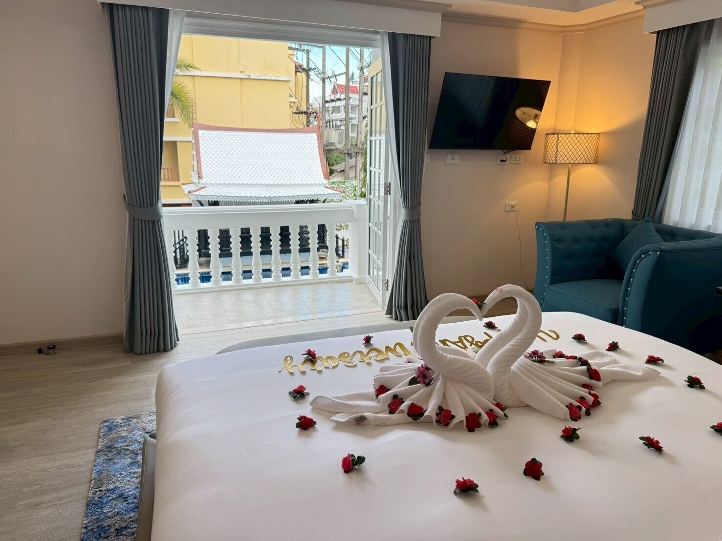 Habitación de hotel con cama, televisión, balcón y vistas al exterior.