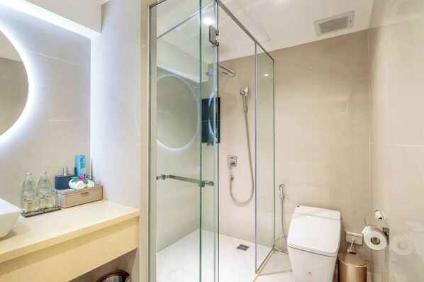 A modern bathroom with a glass-enclosed shower, a toilet, and a vanity with toiletries. - Villa Atchara (Patong)
