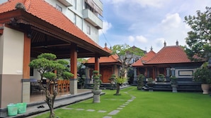 A traditional building with a red-tiled roof, a covered outdoor seating area, and a well-maintained garden with stone pathways. - Ayuna Guest House (Celuk)