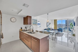 A modern apartment with a kitchen, dining area, and a balcony with a city view.