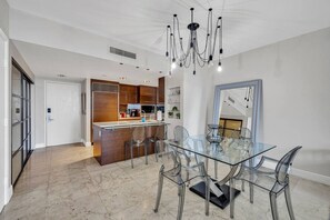 Una cocina moderna con armarios de madera oscura, una isla de cristal y un comedor con mesa y sillas de cristal.