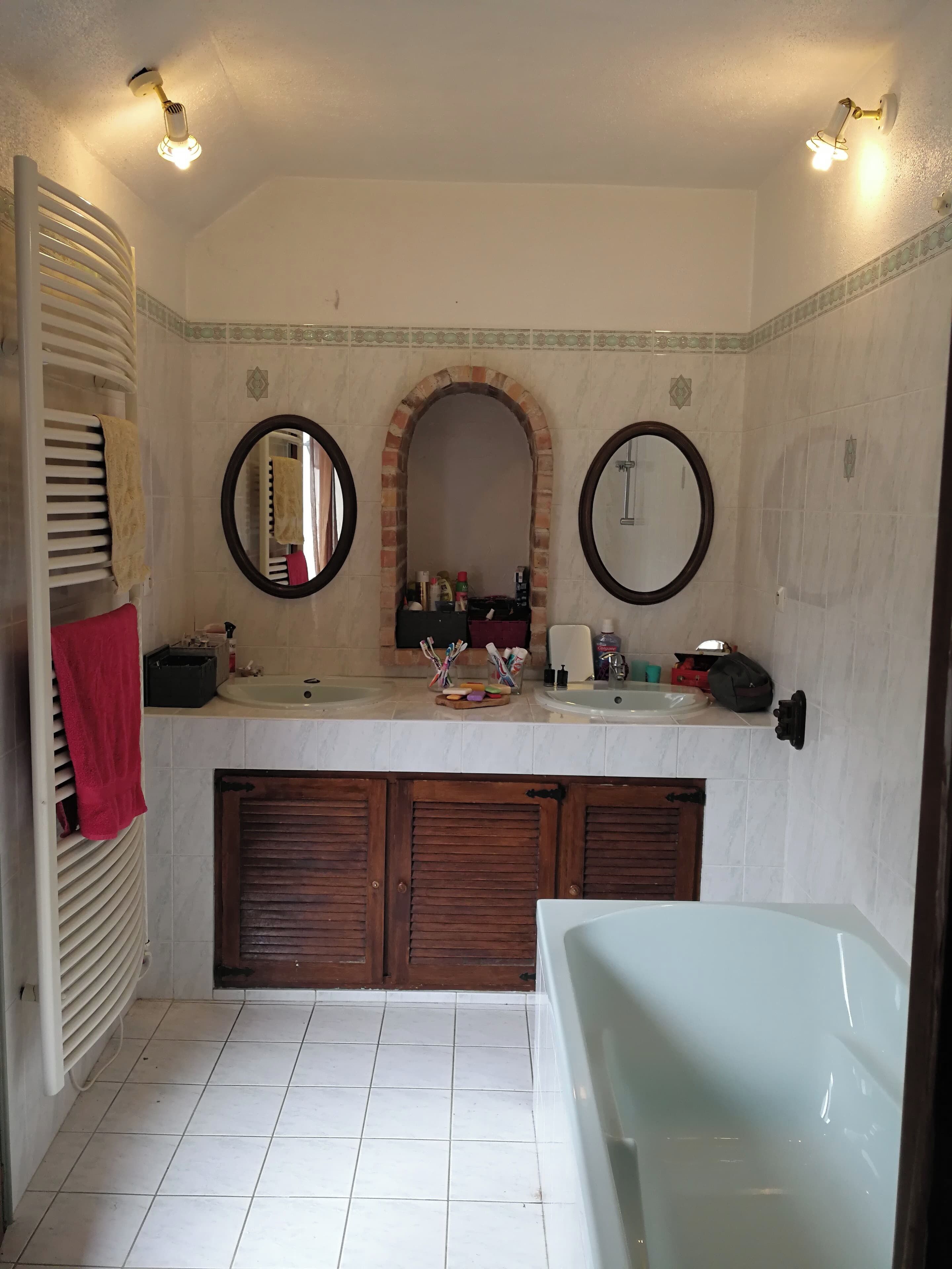 Ein Badezimmer mit einer Badewanne, zwei Waschbecken, einem Spiegel und einem Handtuchhalter.