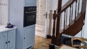 Een keuken met een witte koelkast, een fornuis en een eettafel met honingraat tegels.