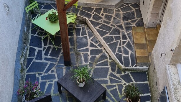 Een binnenplaats met een pergola, stenen vloer en potplanten.