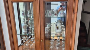 Een houten kast met glazen deuren, gevuld met keukengerei.