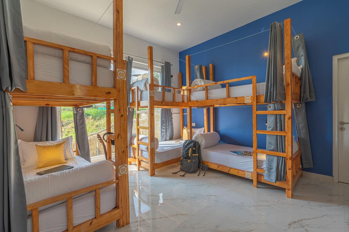A room with bunk beds, a ladder, and a backpack on the floor.