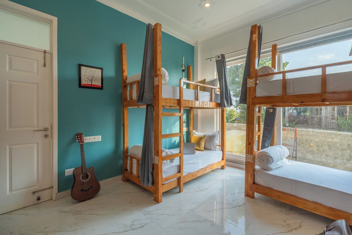 A room with two bunk beds, a guitar, and a window with a view.
