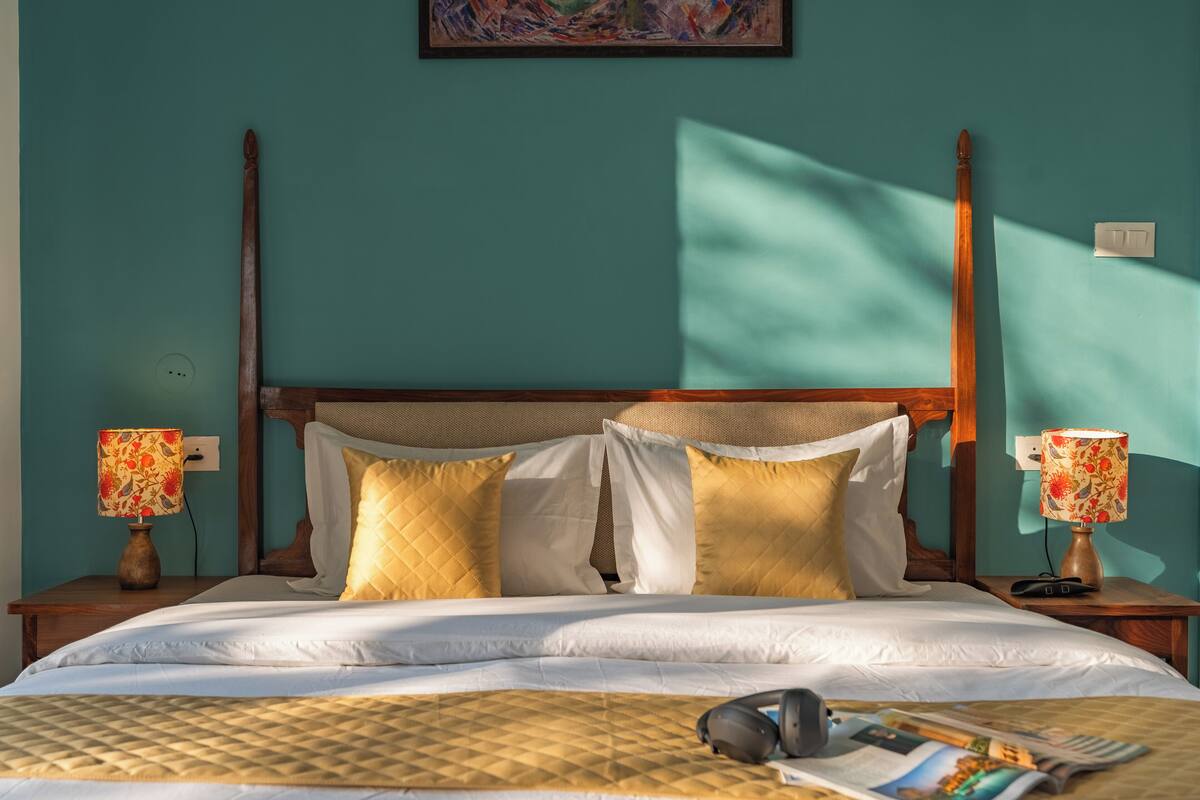 A neatly made bed with a quilted cover, two bedside lamps with floral designs, and a wooden headboard.