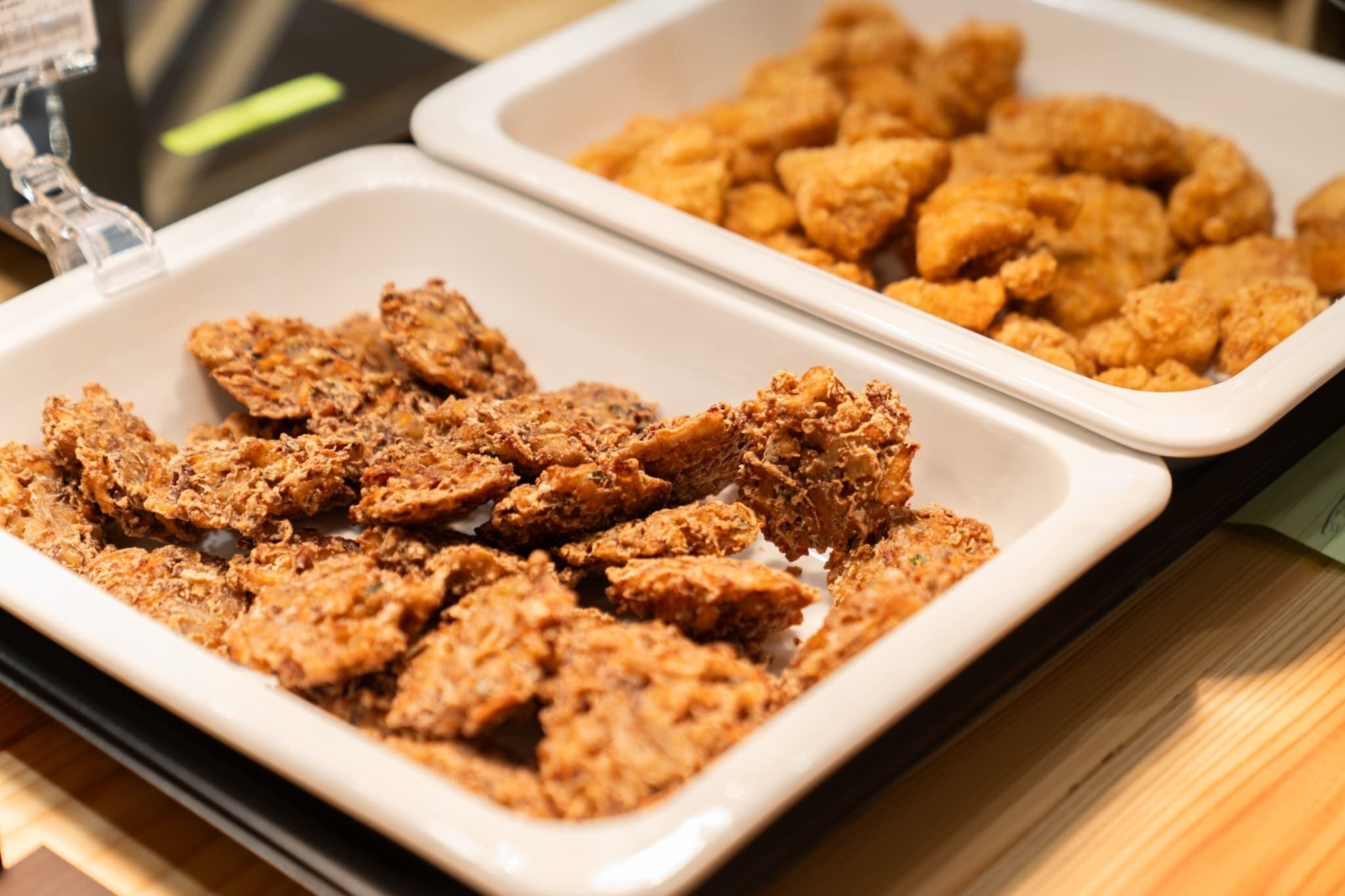 A buffet with two trays of fried chicken.