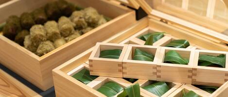 A wooden box with compartments containing green leaves and a separate compartment with green leaves and a wooden tray.