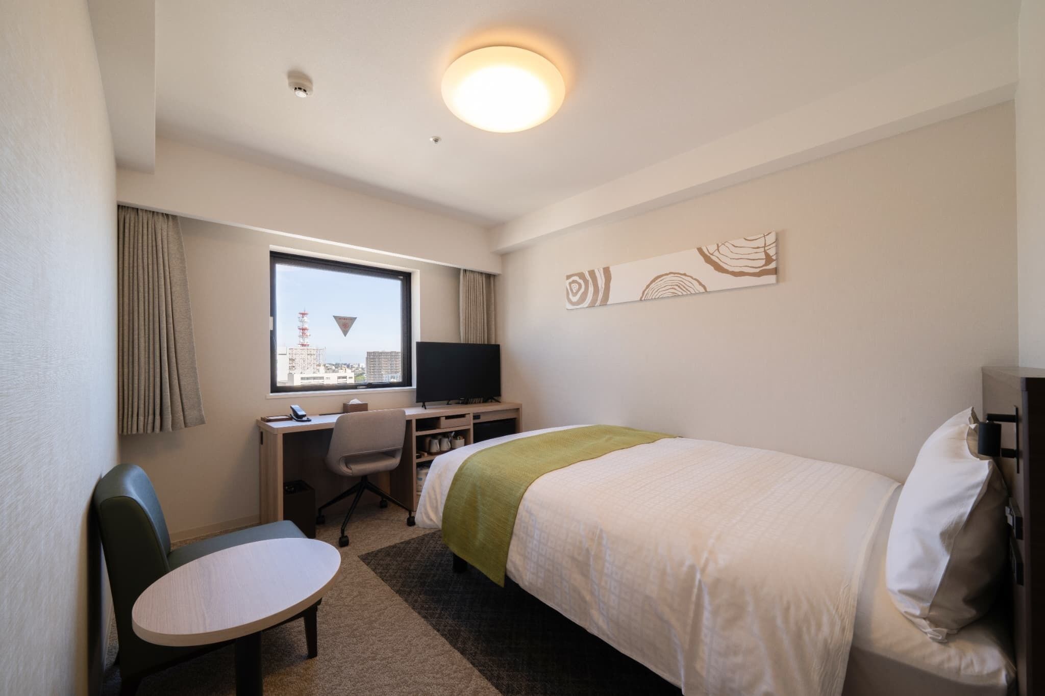 Une chambre d’hôtel équipée d’un lit, d’un bureau, d’une chaise et d’un téléviseur.