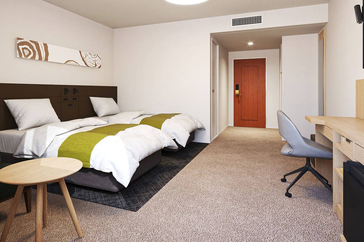 Una habitación de hotel con una cama, un escritorio, una silla y una pequeña mesa.