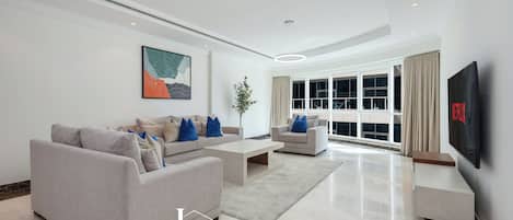 A modern living room with a sofa set, coffee table, and a TV mounted on the wall.
