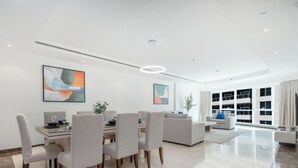 Un espacio habitable moderno y bien iluminado, con una mesa de comedor y sillas, un sofá, y ventanas amplias que ofrecen vistas.
