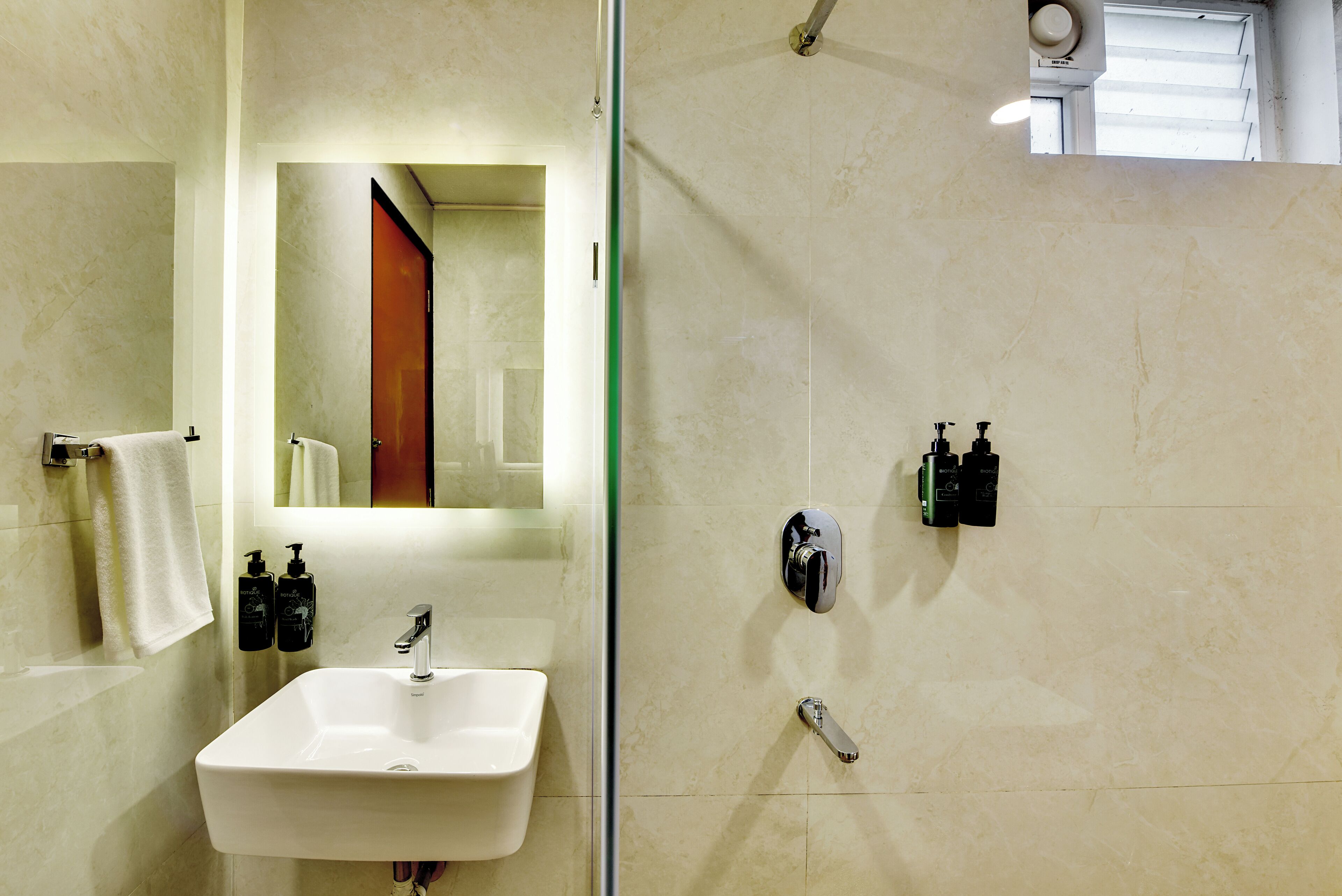 Une salle de bain avec un lavabo blanc, un miroir et deux distributeurs de savon noirs.