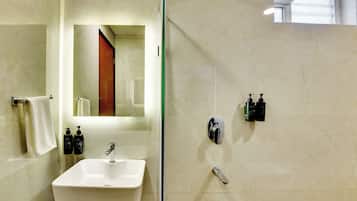 Une salle de bain avec un lavabo blanc, un miroir et deux distributeurs de savon noirs.